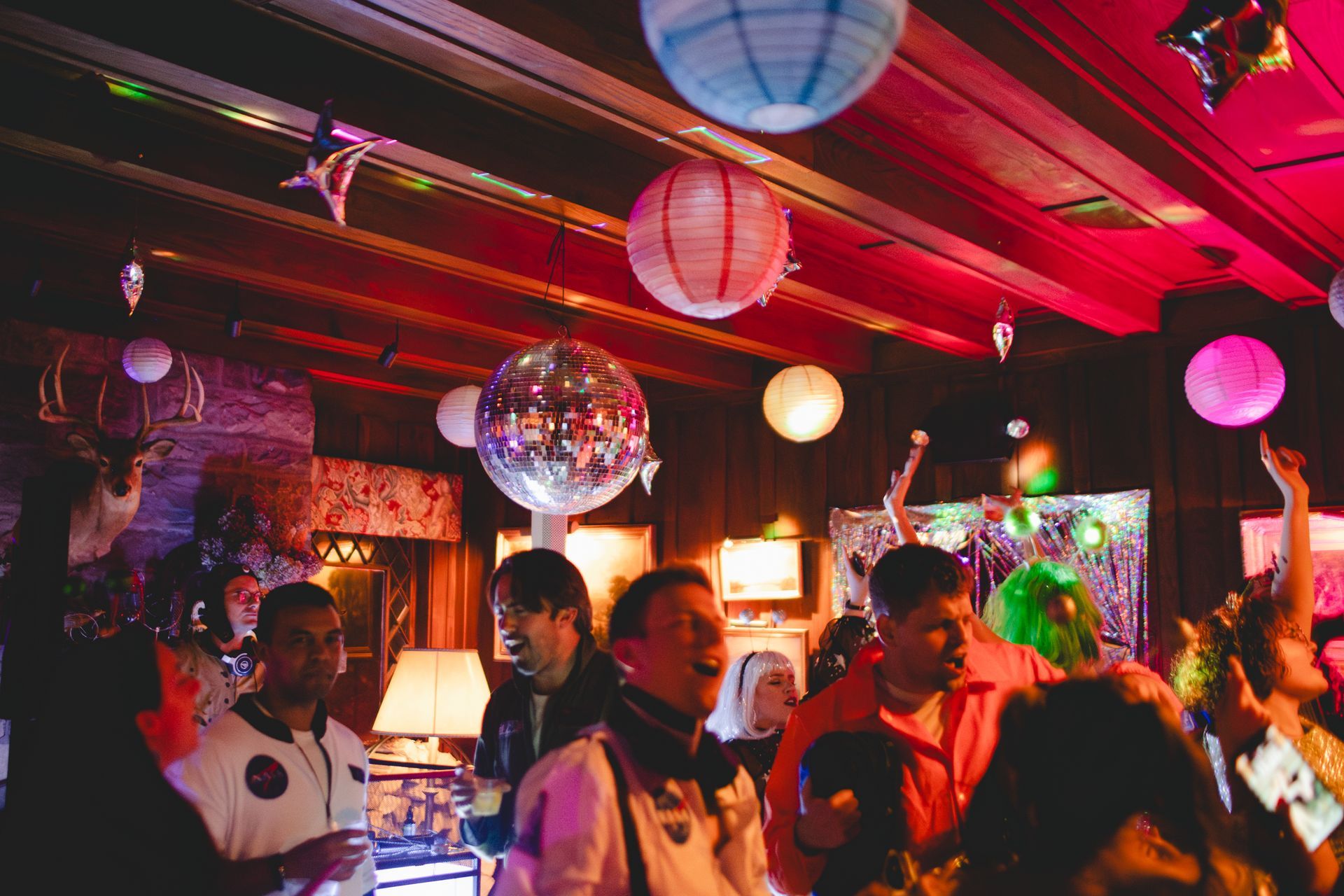 A group of people are dancing in a room with balloons hanging from the ceiling.
