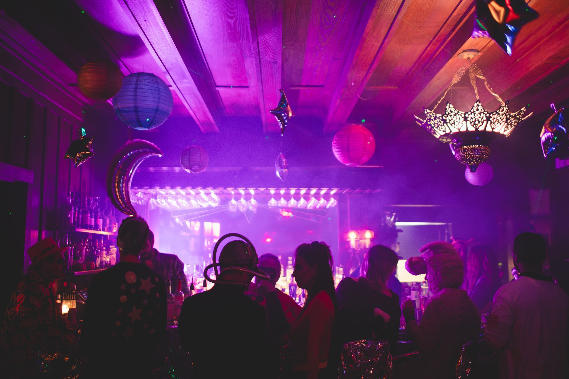 A group of people are standing in a dark room with purple lights.