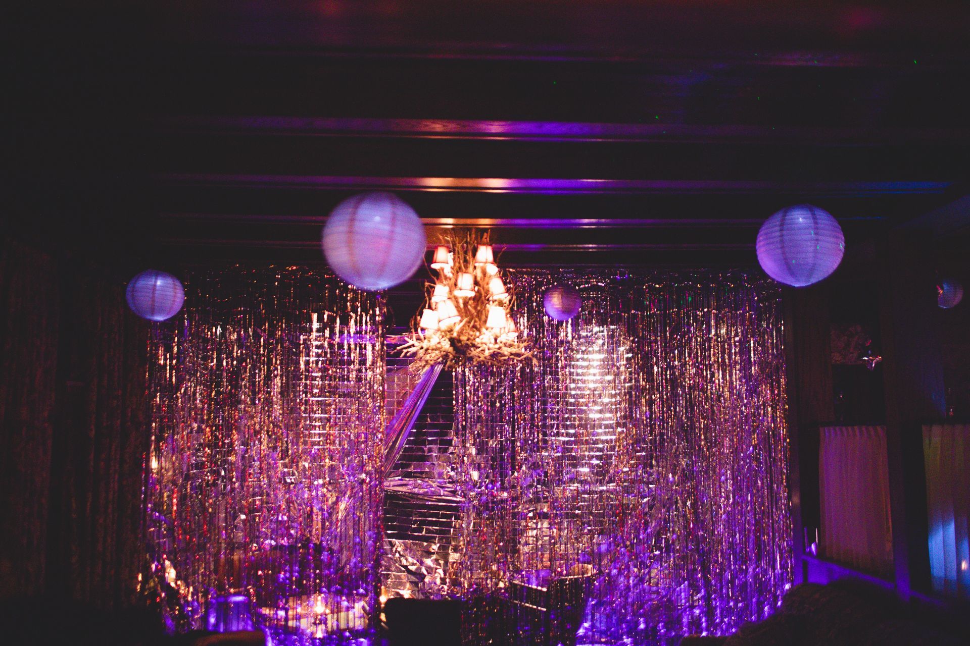 A stage in a dark room with purple lights and a chandelier.