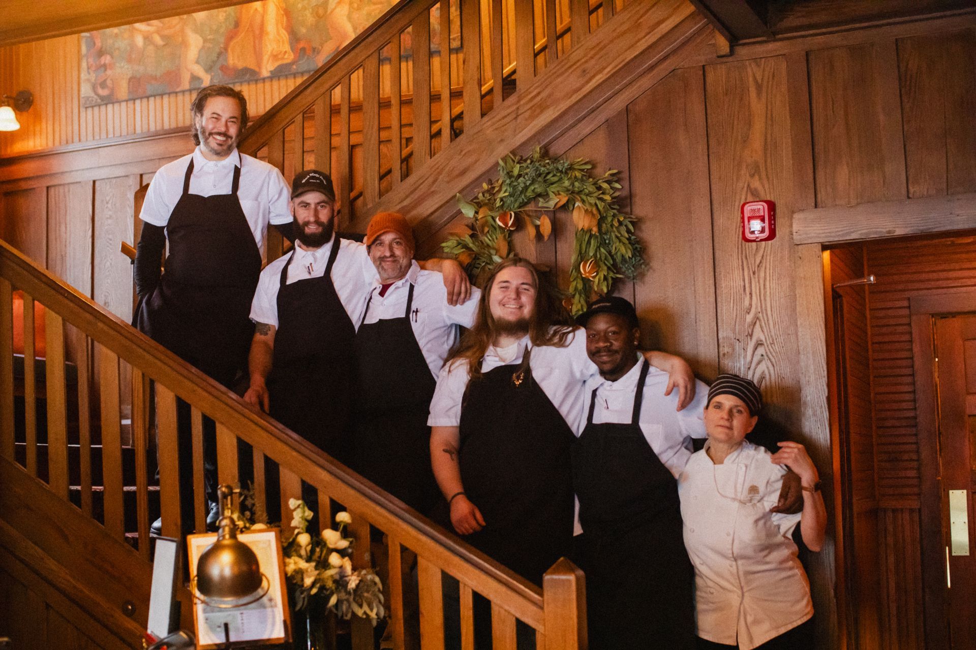 A group of chefs are posing for a picture on a wooden staircase.
