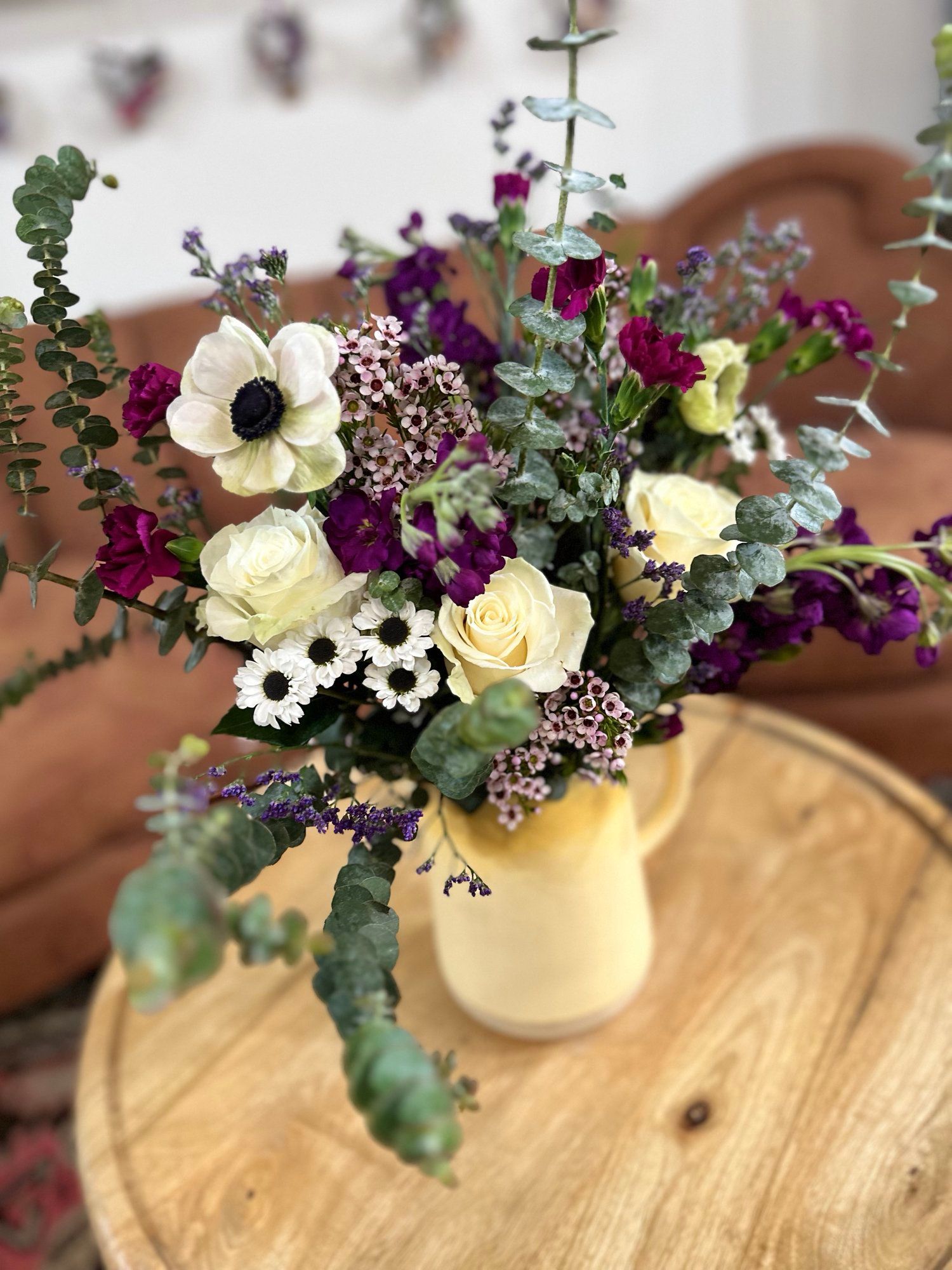 A vase filled with flowers is sitting on a wooden table.