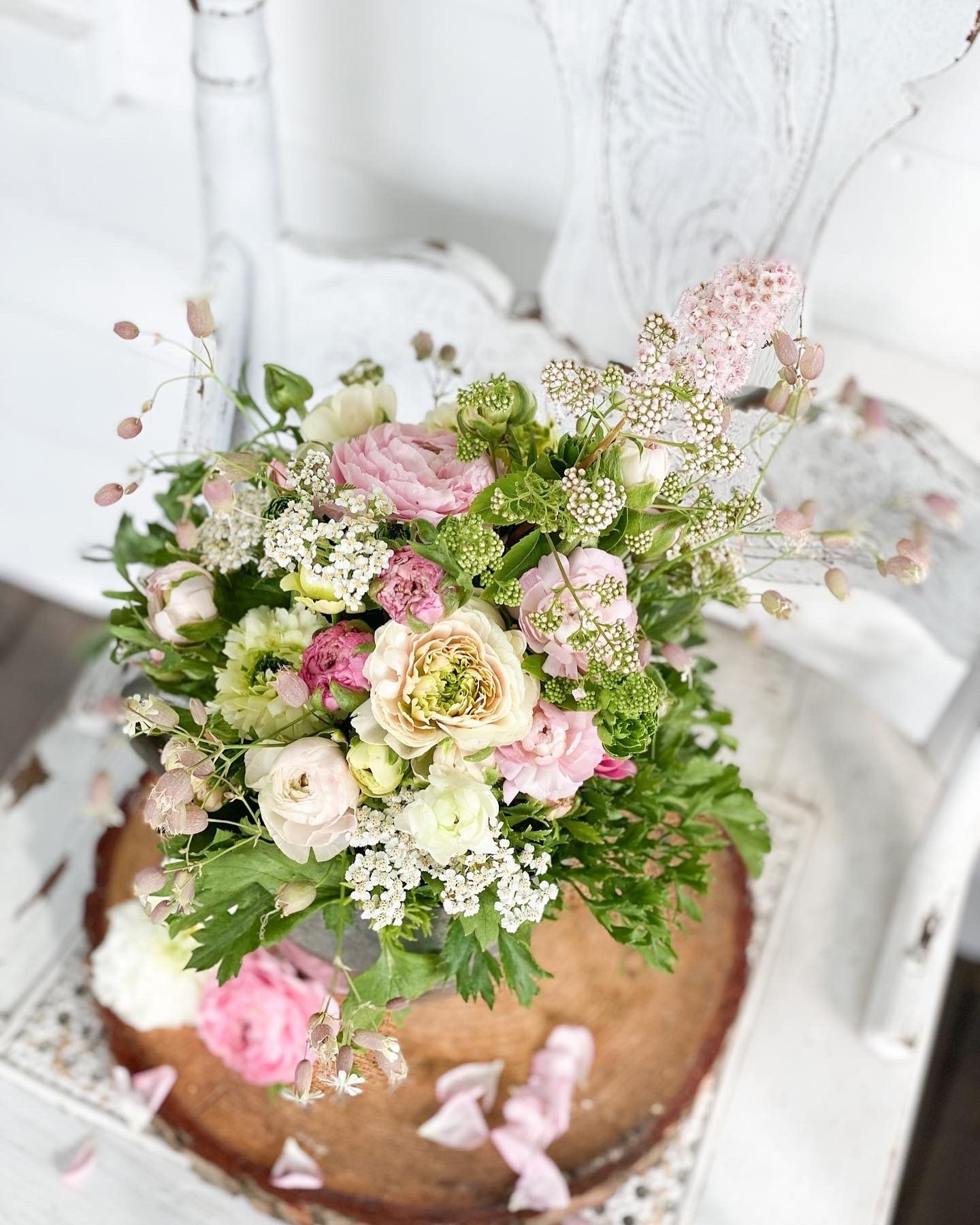 A bouquet of flowers is sitting on top of a wooden slice on a table.