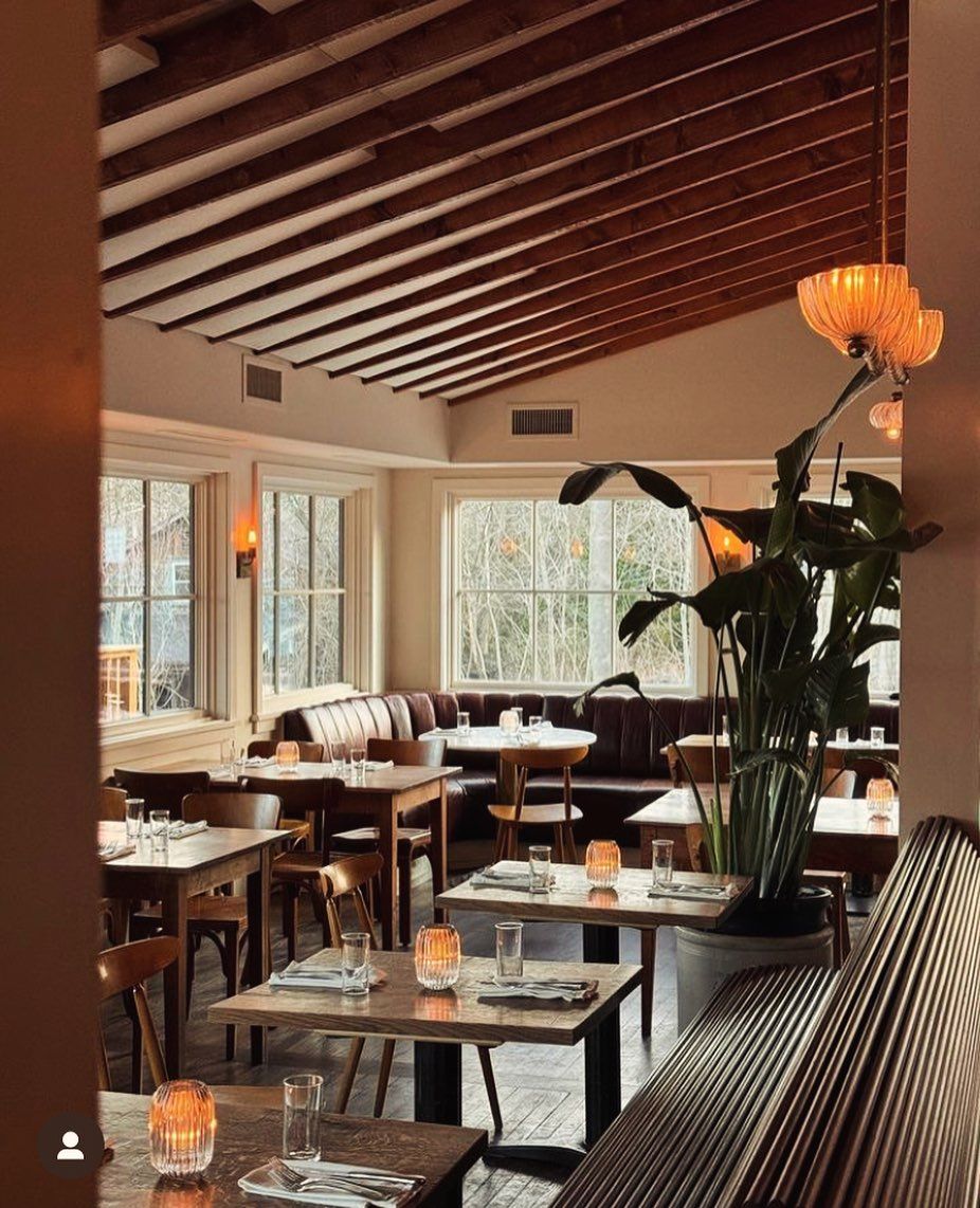 A restaurant with tables and chairs and a plant in the middle of the room.