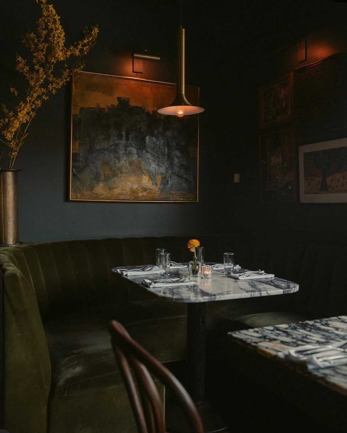 A dark room with a table and chairs and a painting on the wall