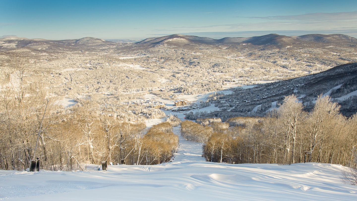 A person is skiing down a snow covered slope in the mountains.