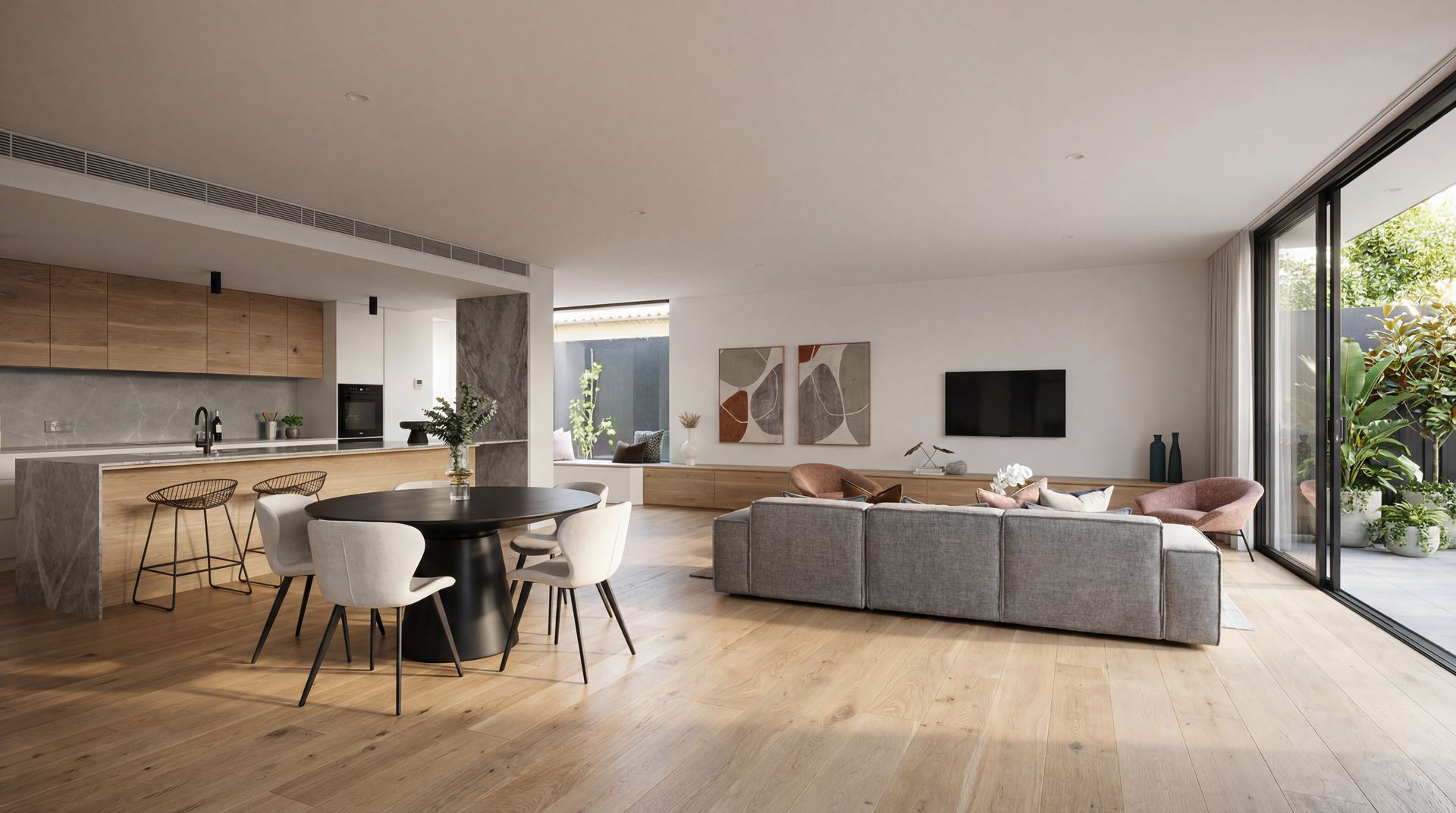 Modern open-plan living room with gray sectional, dining table, kitchen, and large glass doors to a garden