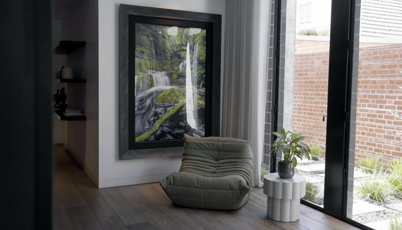 Modern living room with a waterfall painting, green chair, and floor-to-ceiling windows overlooking a brick wall