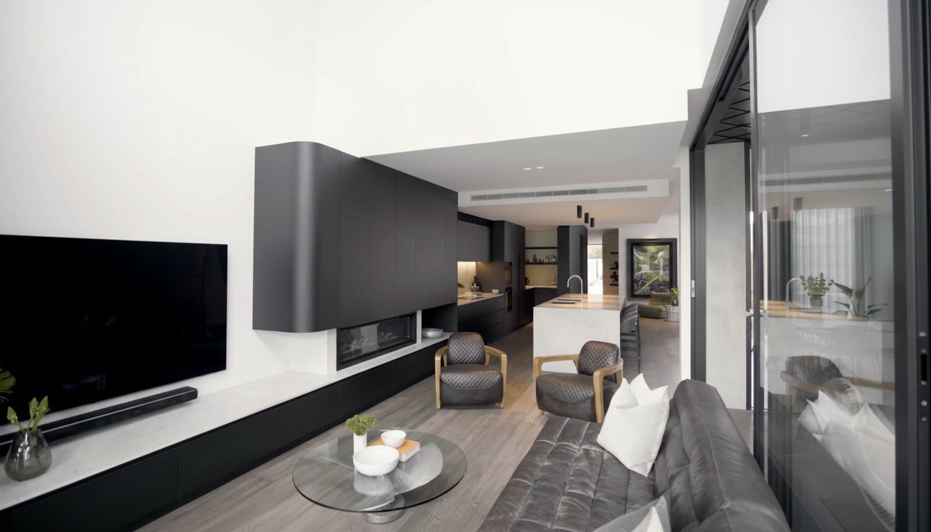 Modern living room and balcony with gray sectional, wall TV, coffee table, and open view to bright interior space