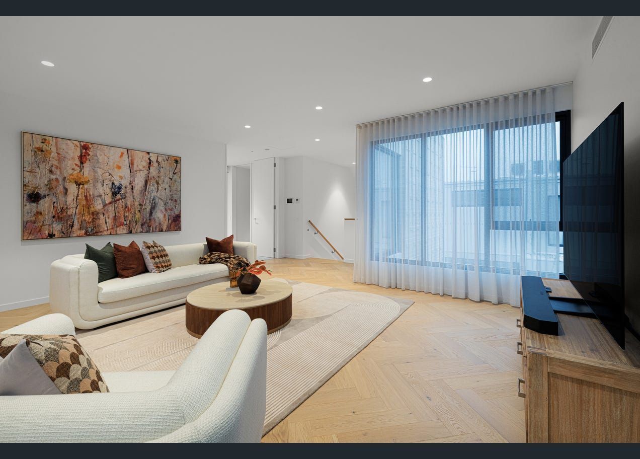 Modern living room with white sofas, abstract art, large TV, and floor-to-ceiling sheer curtains.