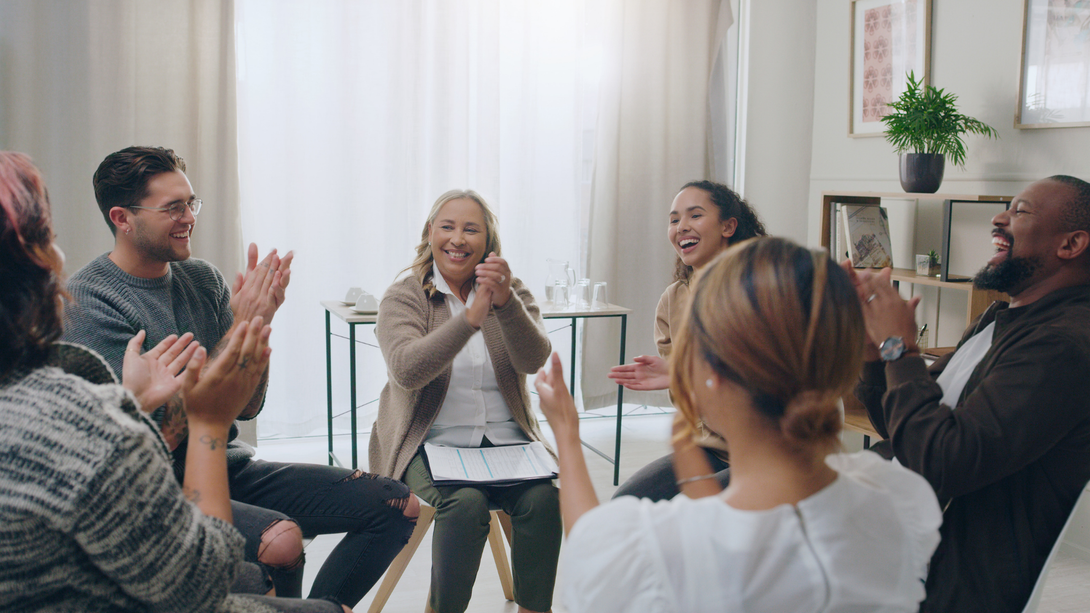 Group in a counseling session, seated in a circle, with one person speaking and others listening.