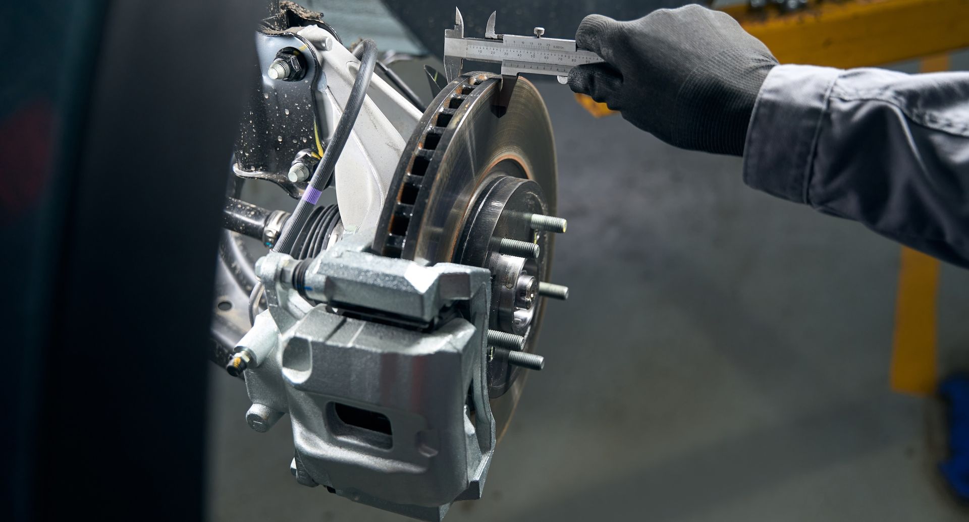 A man is measuring a brake disc with a caliper.