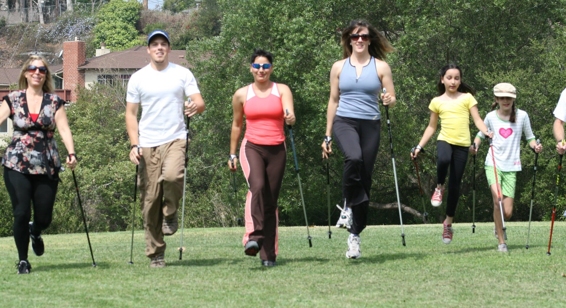 A group of people are walking in a park with walking poles