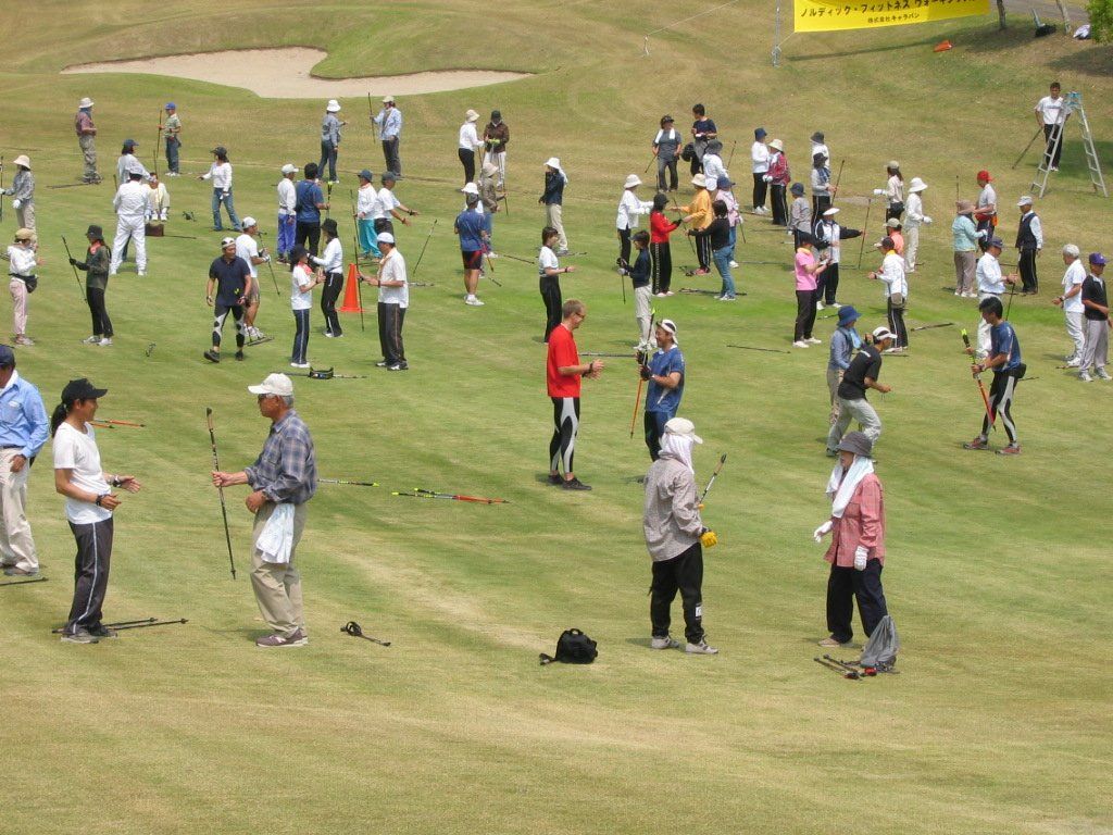 A large group of people are playing golf on a lush green field