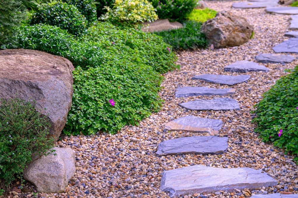 Stone path through a green garden with gravel and large rocks