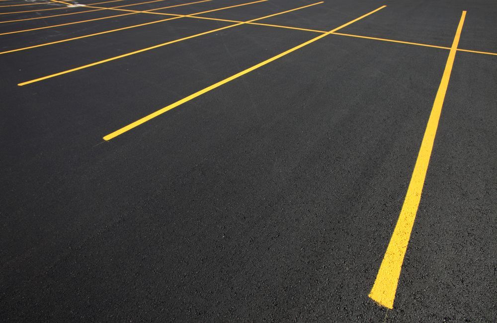 Empty asphalt parking lot with bright yellow painted lines angled across the pavement