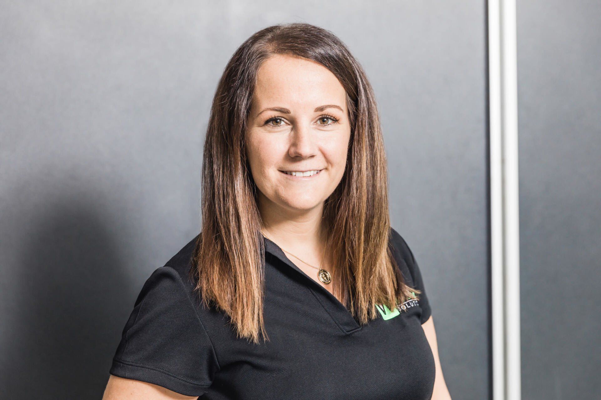 A woman in a black shirt is smiling in front of a blackboard.