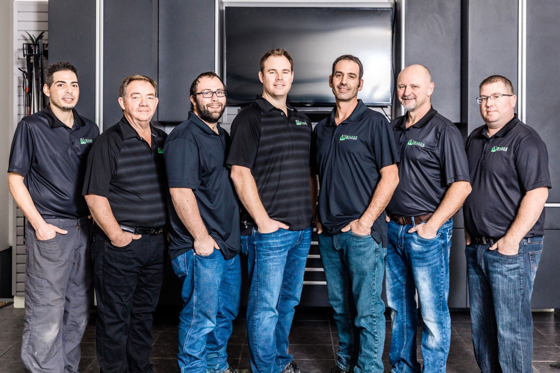 A group of men standing next to each other in front of a television.