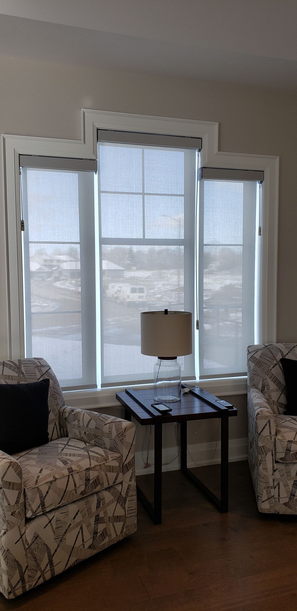 A living room with two chairs , a table , and a lamp.