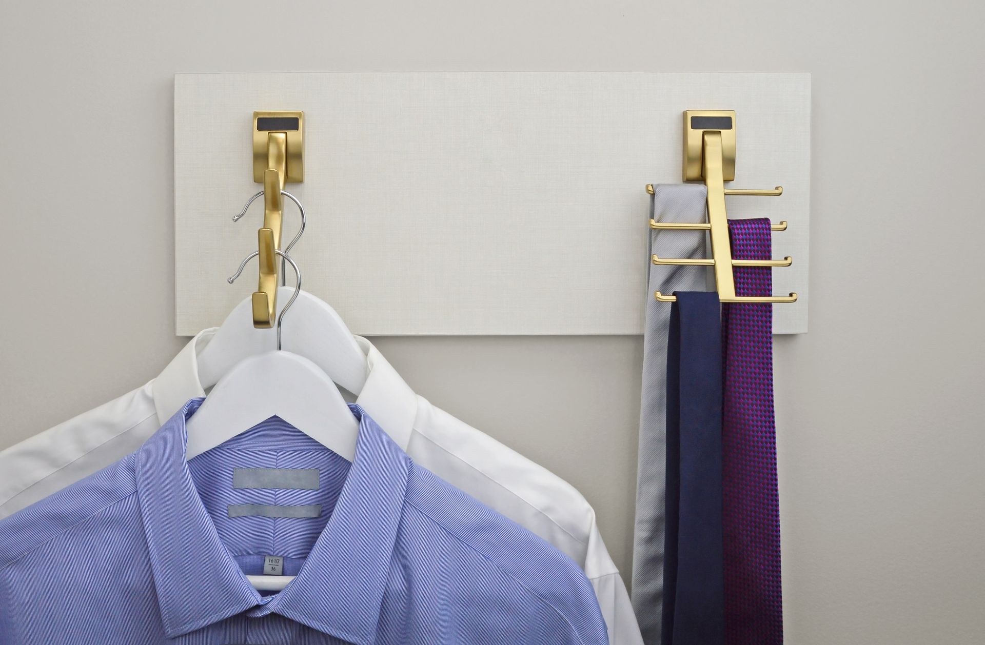 A blue shirt is hanging on a white hanger next to a purple tie.