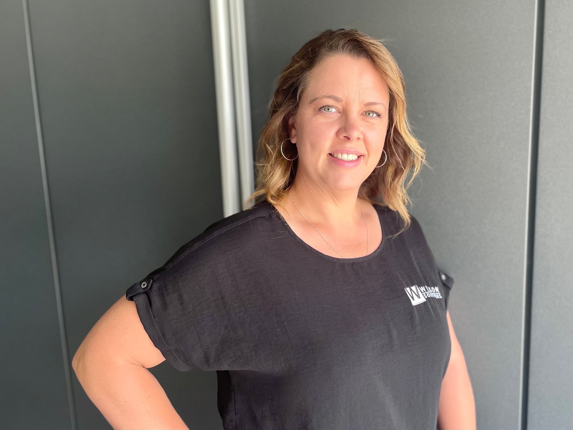 A woman in a black shirt is standing with her hands on her hips.