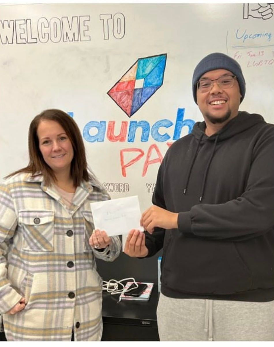 A man and a woman are standing in front of a sign that says welcome to launch pa