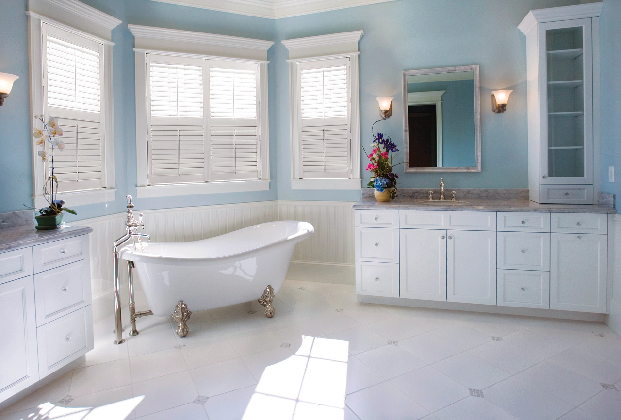 A bathroom with a bathtub , sink , mirror and blue walls.