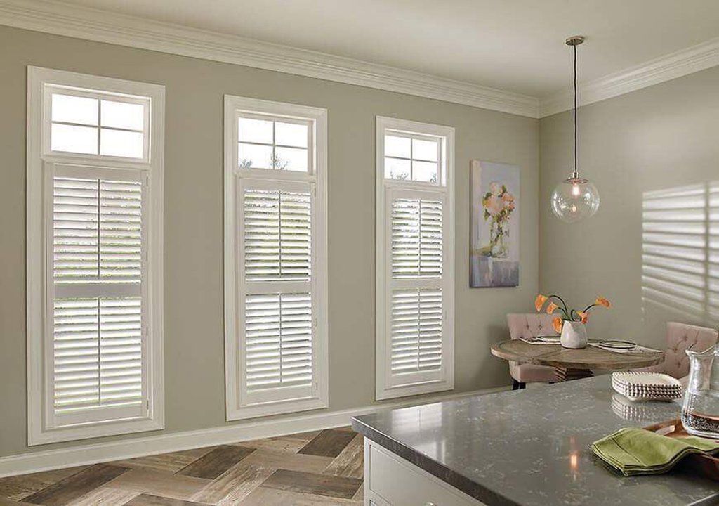 A kitchen with a table and chairs and shutters on the windows.