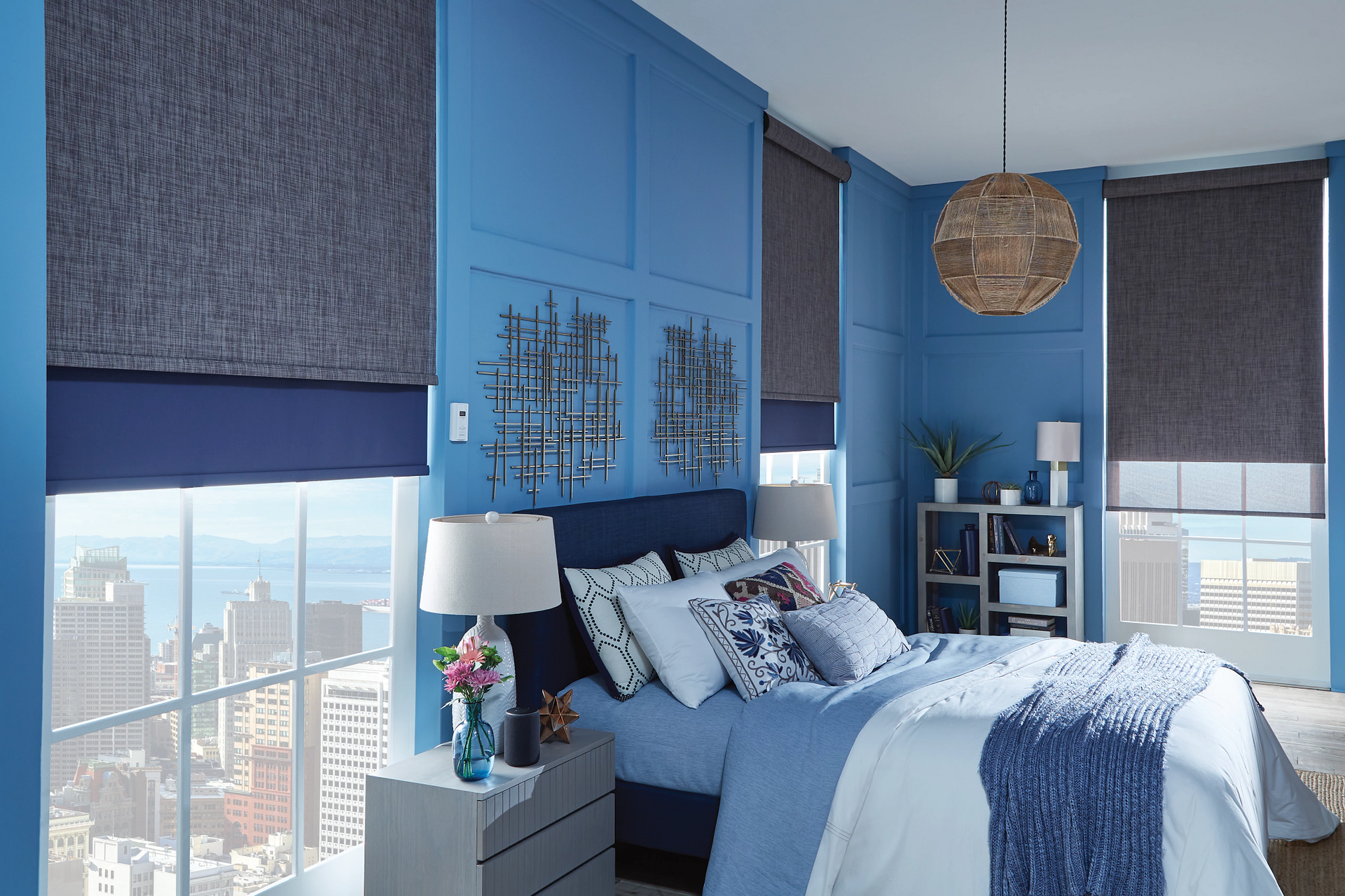 A bedroom with blue walls , a bed , a nightstand , and a window.