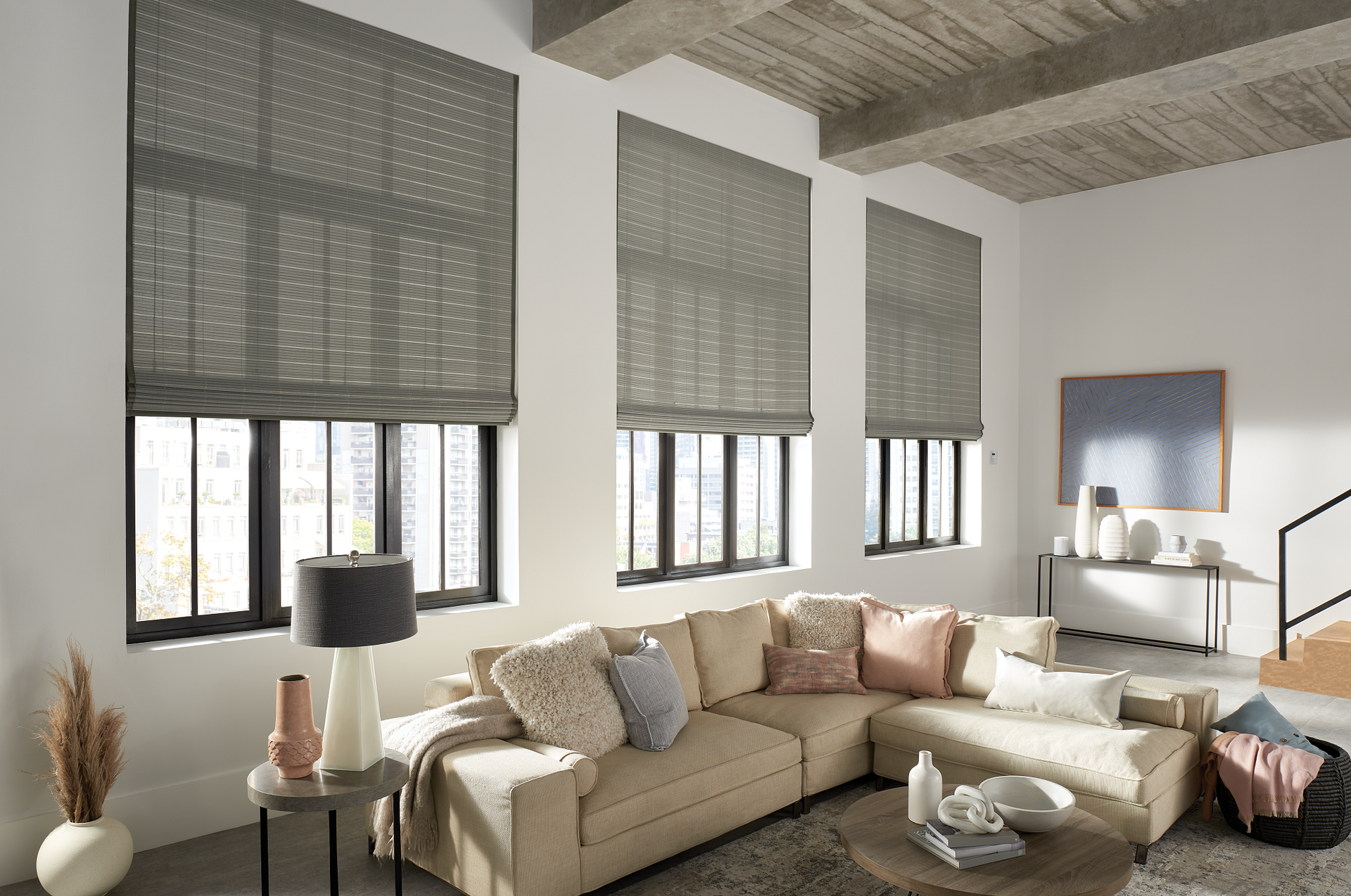 A living room with a couch , table , lamps and windows.