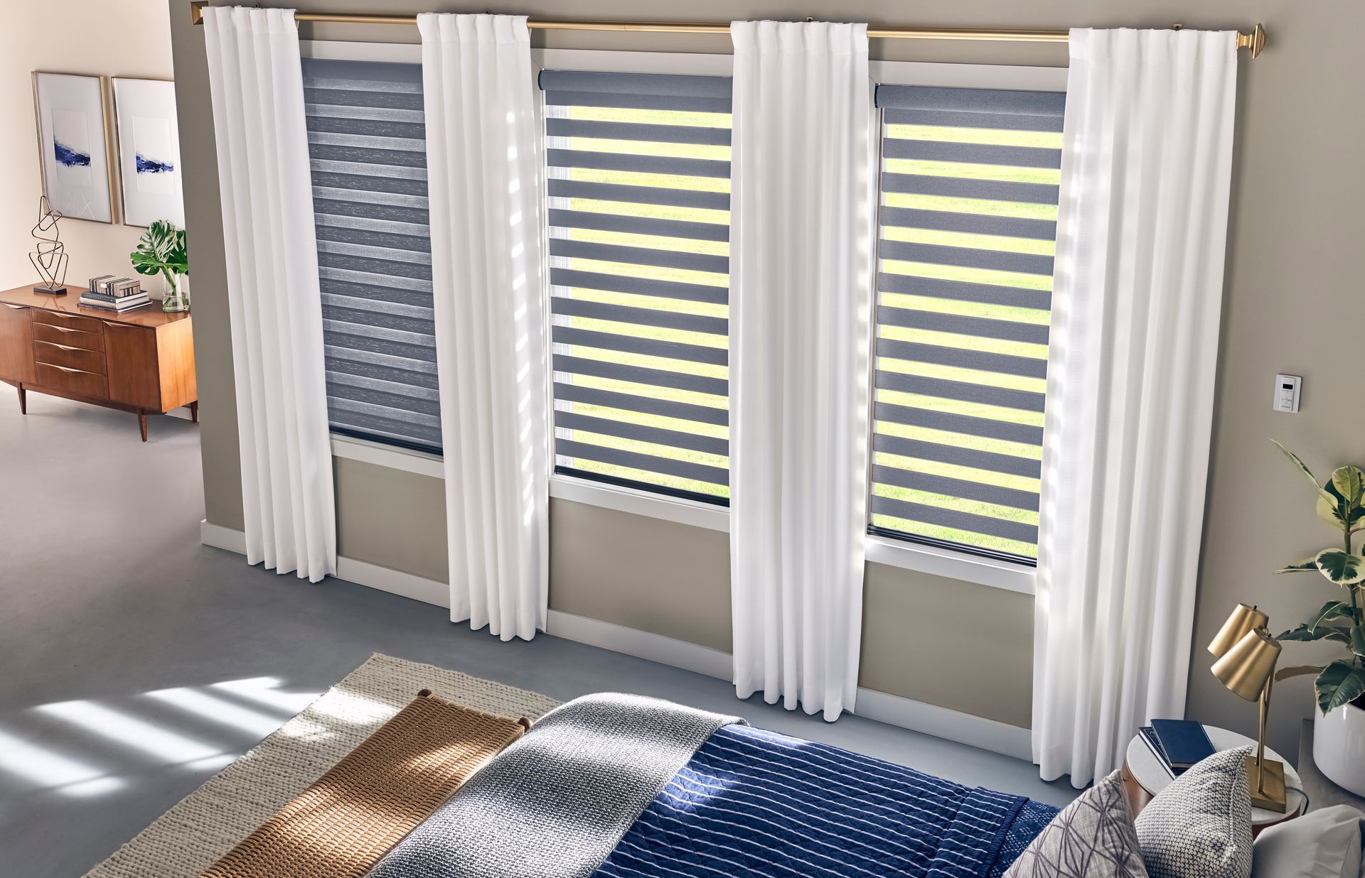 A bedroom with a bed , curtains , and striped blinds.