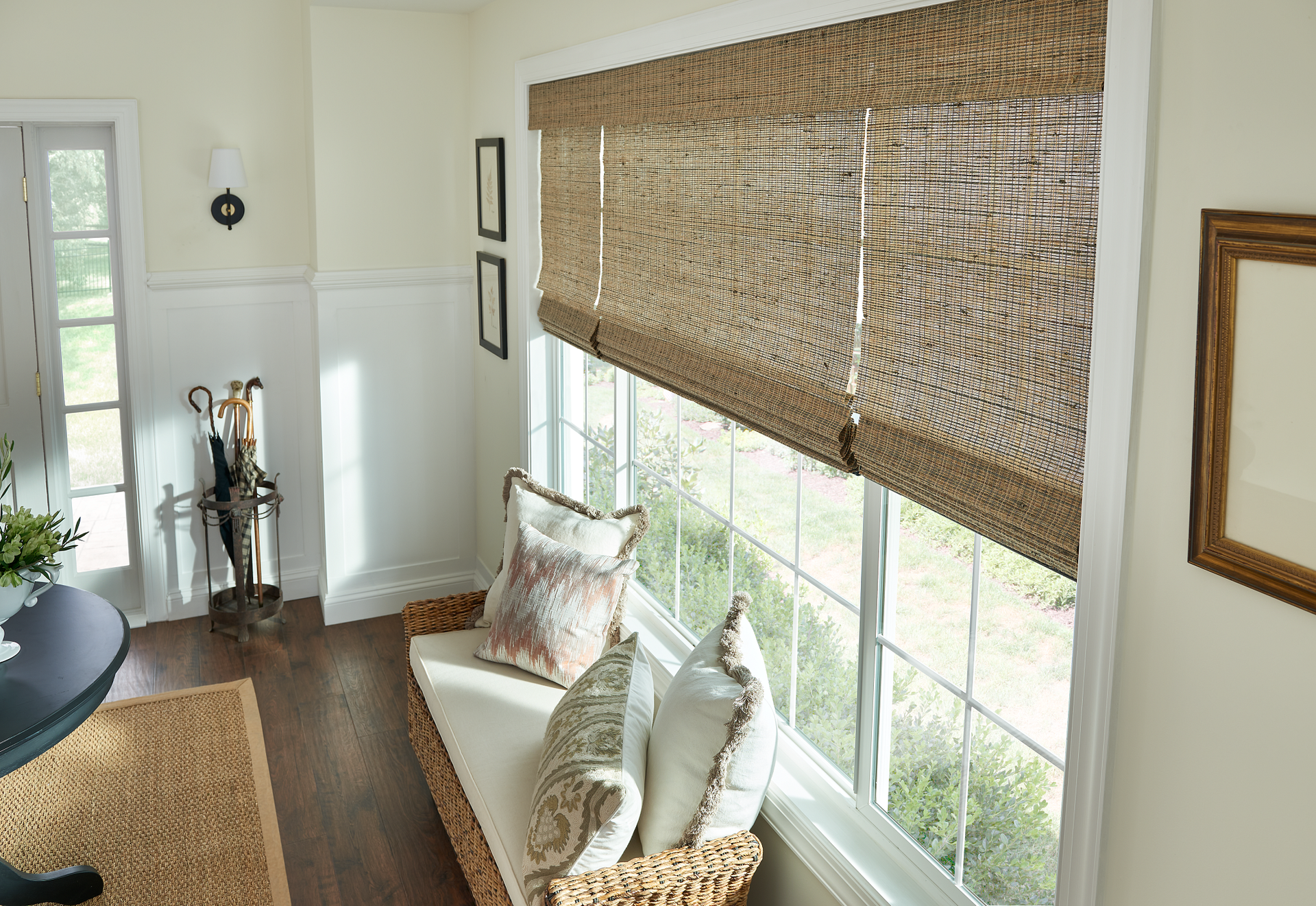 A living room with a couch and a large window with roman shades.
