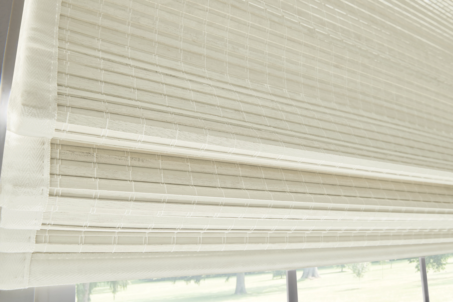A close up of a white roman shade on a window.