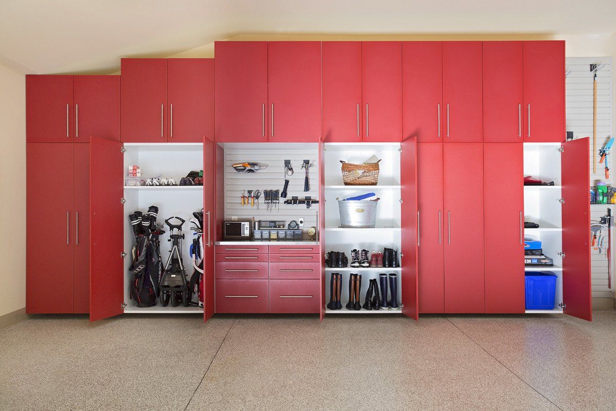 Red built-in cabinets with open shelves holding golf clubs and shoes in a room with a speckled floor