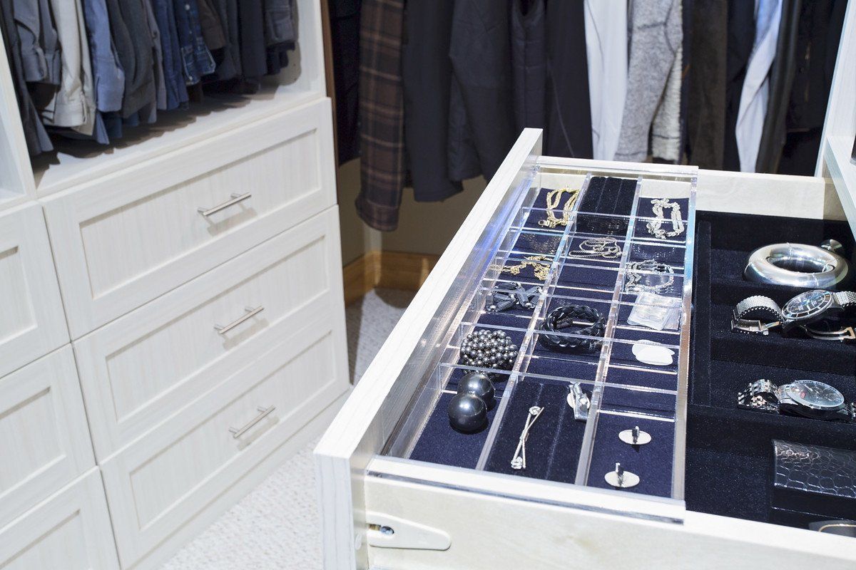 White closet with jewelry drawer open, displaying various accessories.