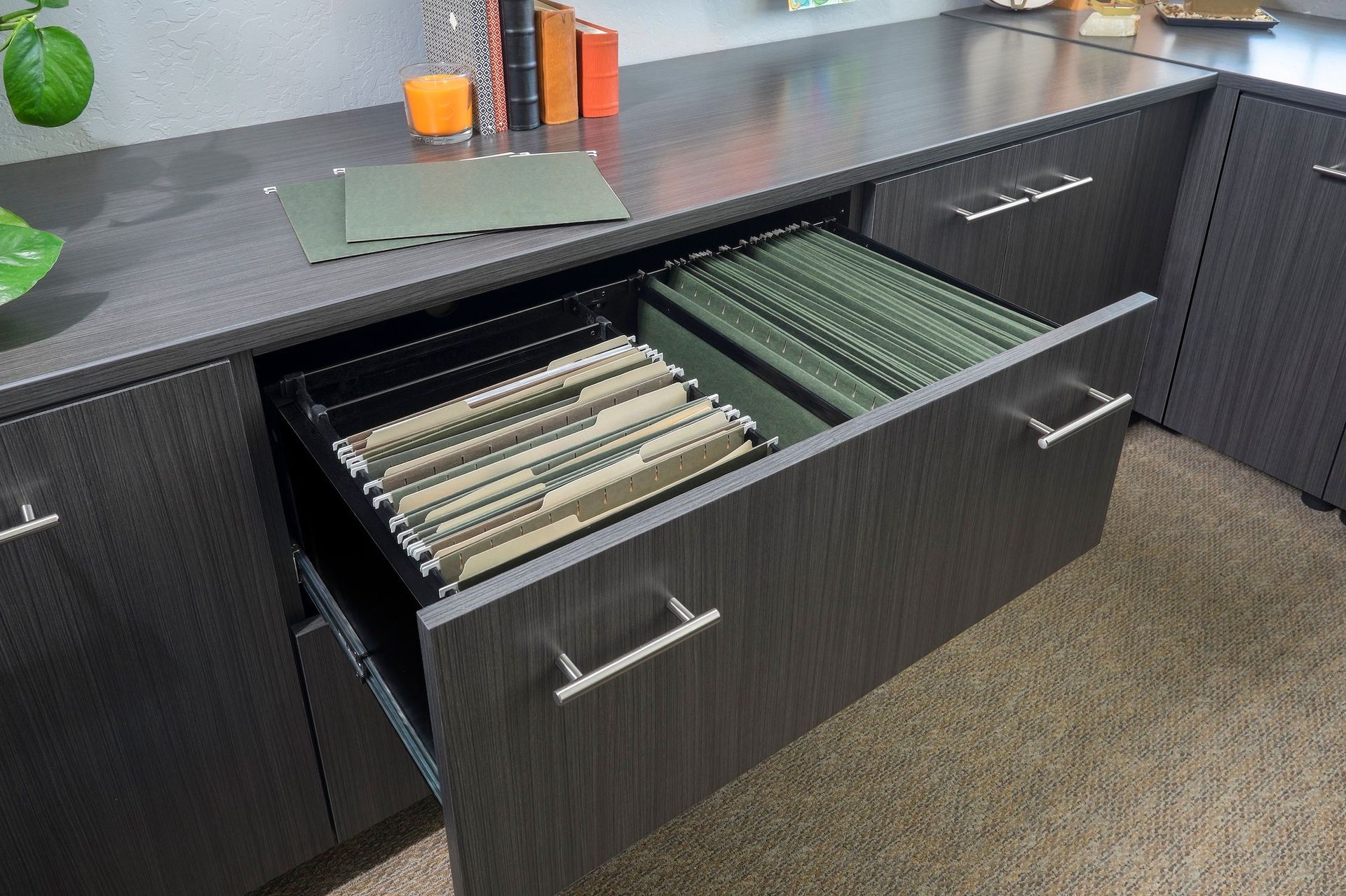 Dark gray desk with an open file drawer filled with hanging folders.