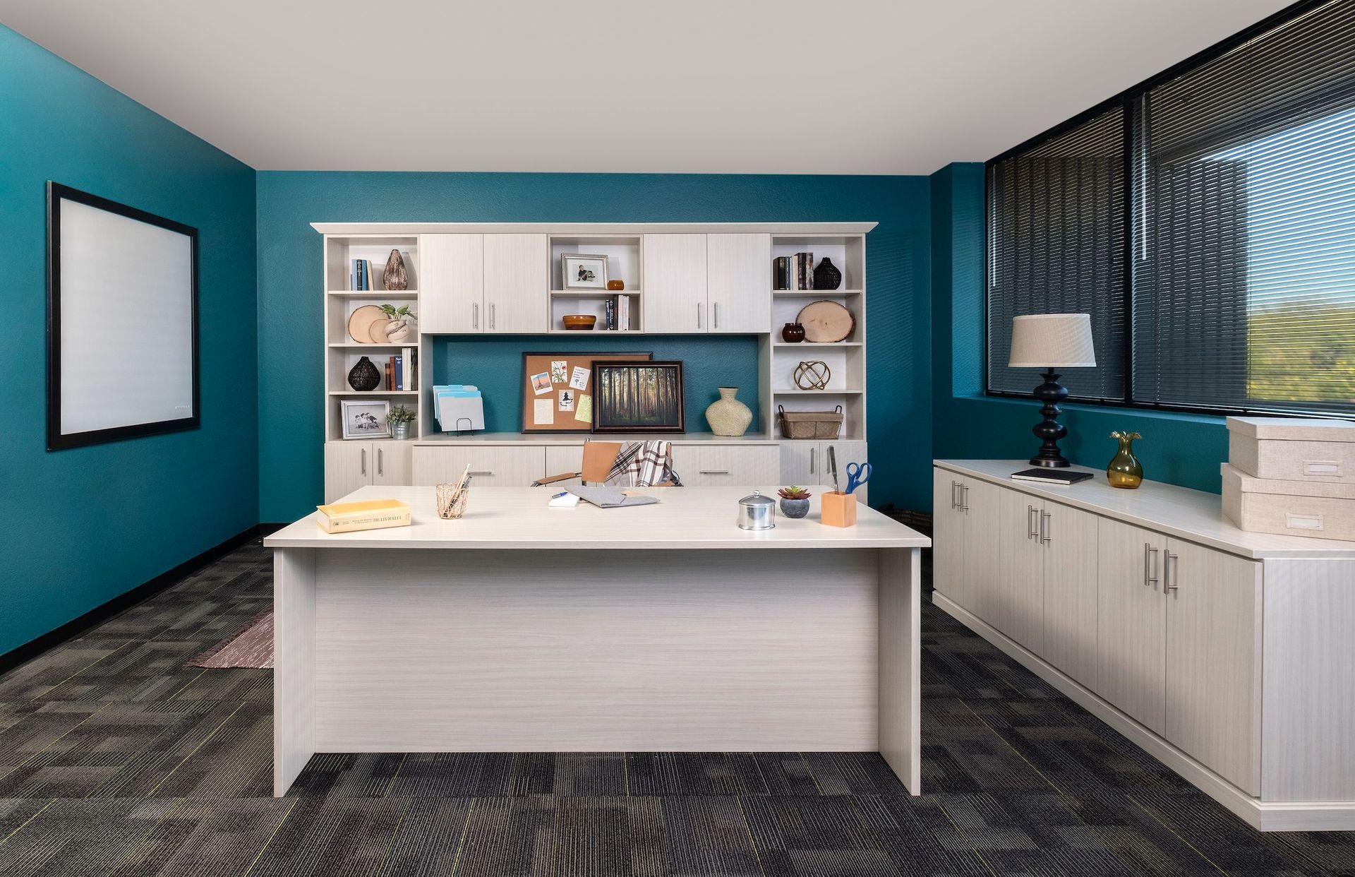 Office with teal walls, white desk, cabinet, and bookshelves. A window is on the right.