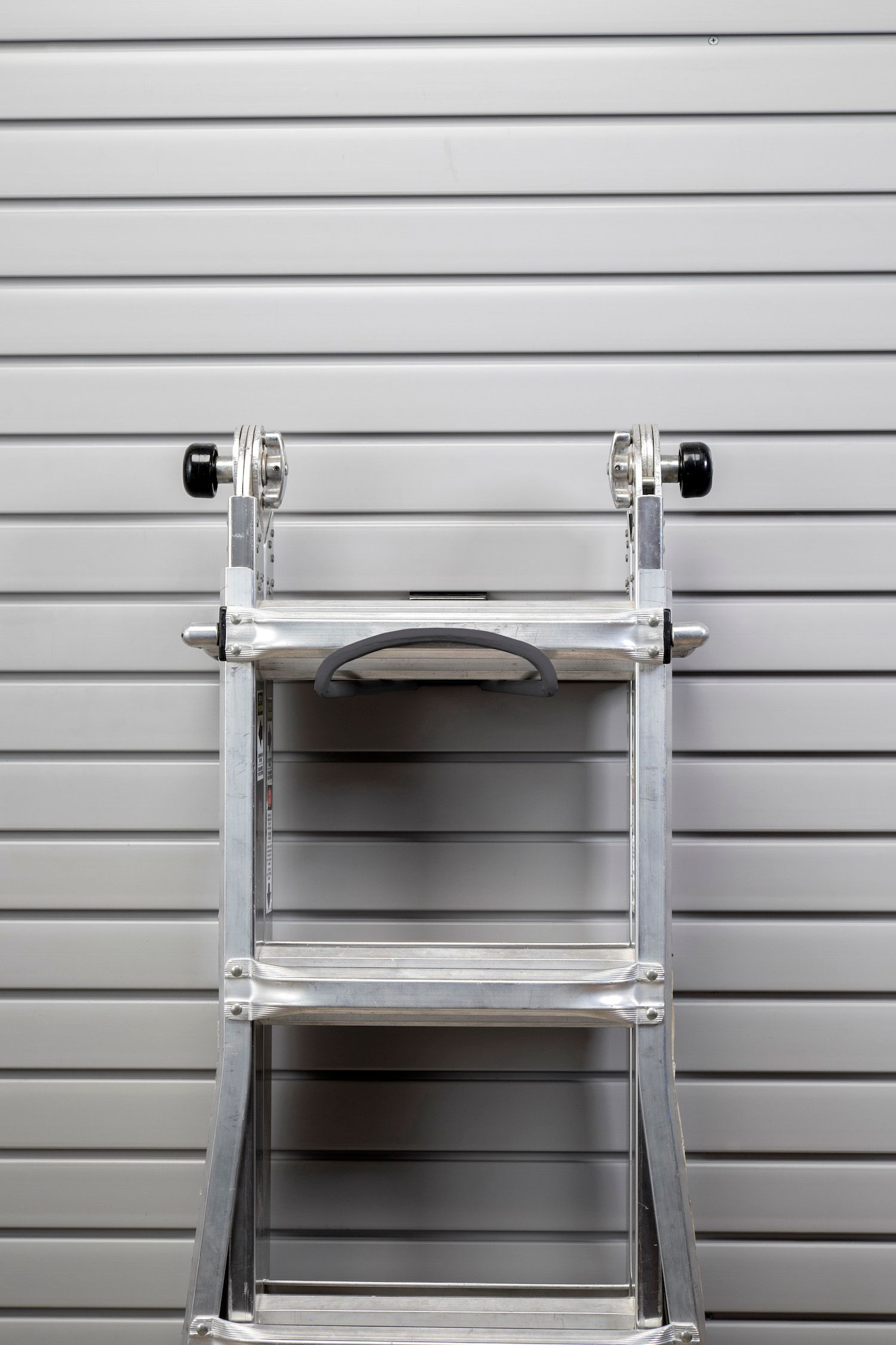 Silver ladder against a gray horizontally-lined wall.