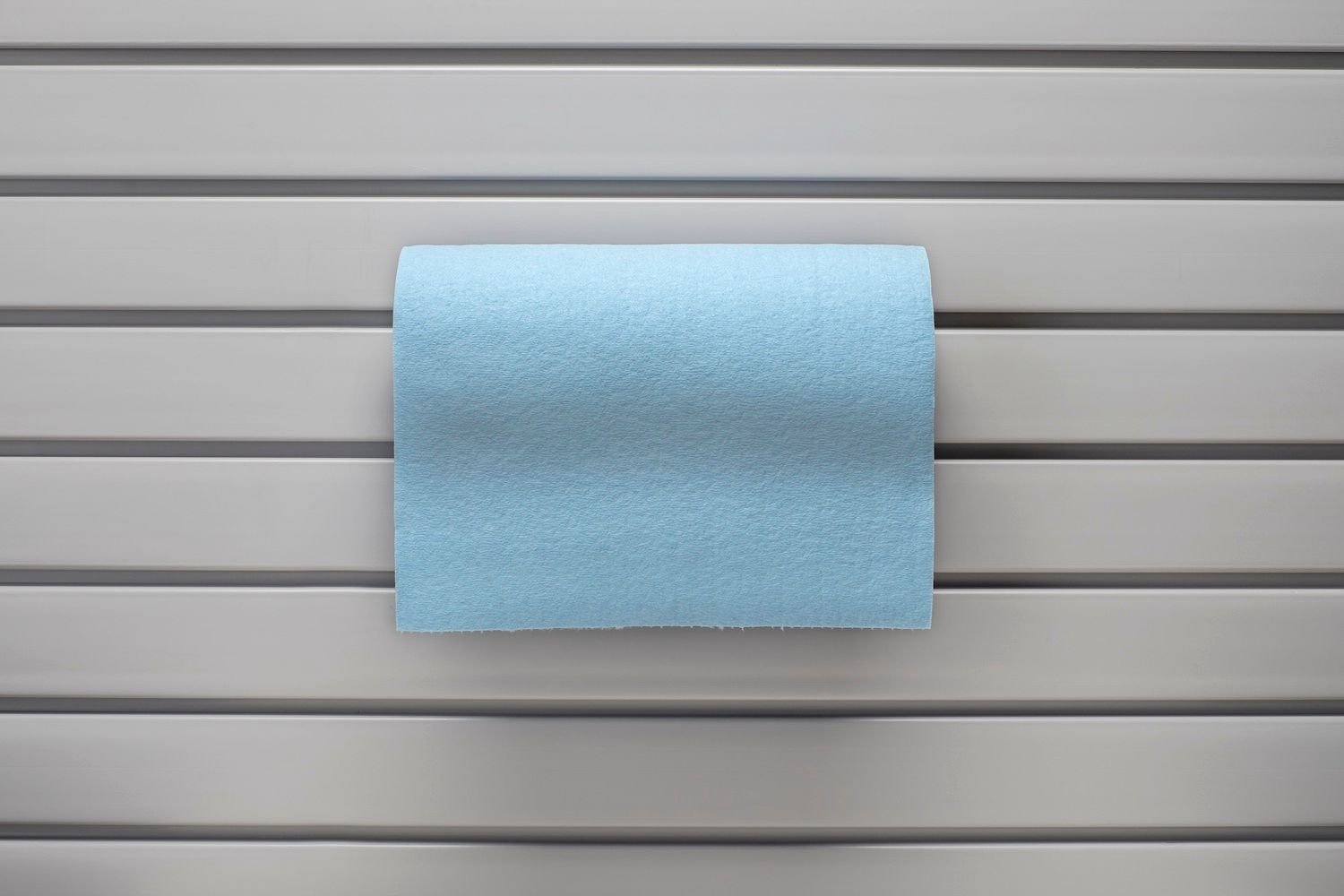 Blue paper towel roll on a gray slatted surface.