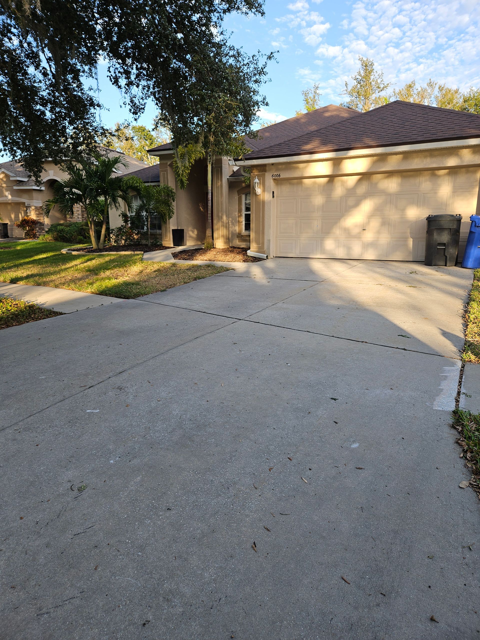 Suburban house with a two-car garage and concrete driveway in late afternoon light