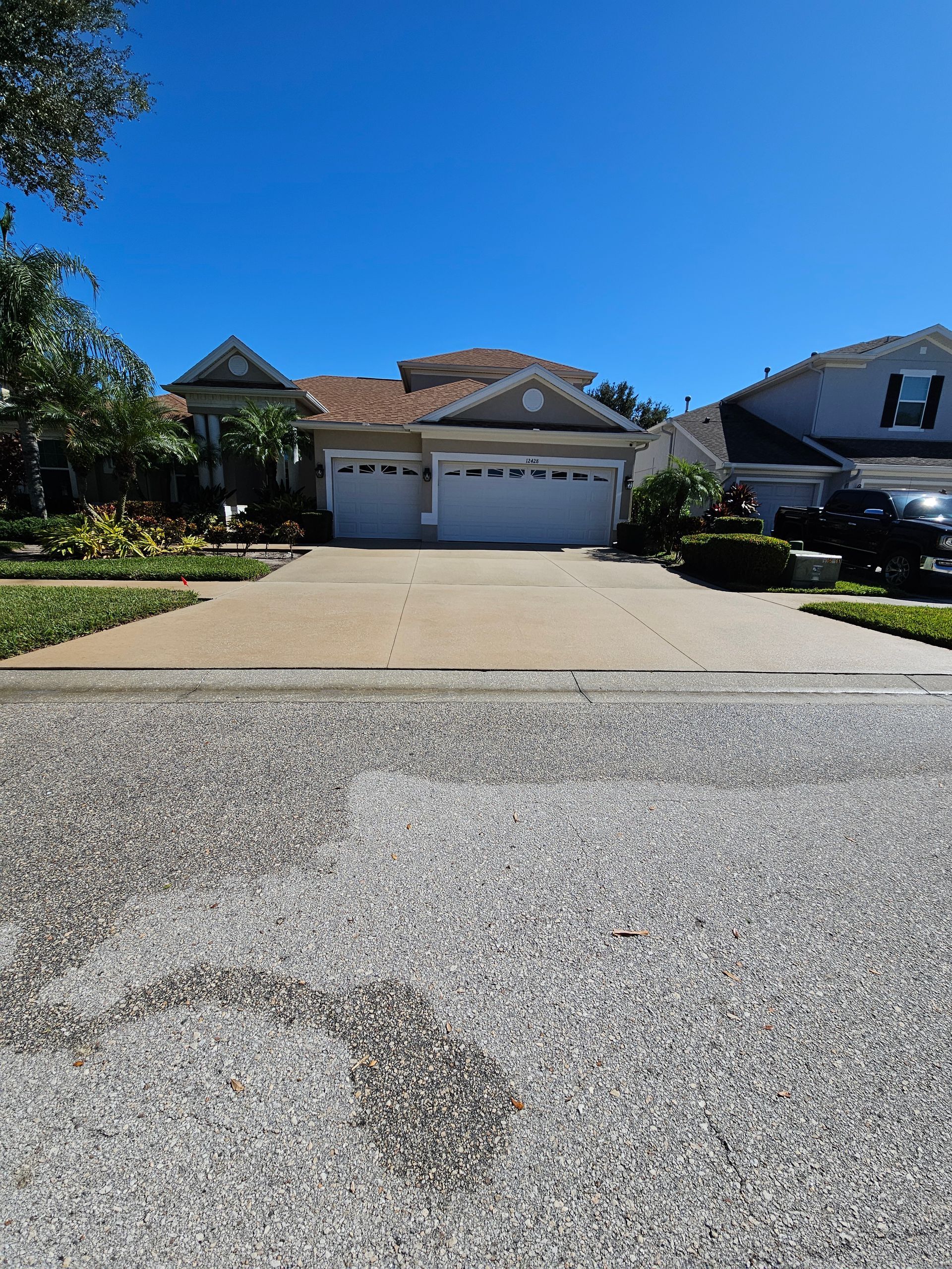 Suburban house with two-car garage, wide driveway, and clear blue sky.