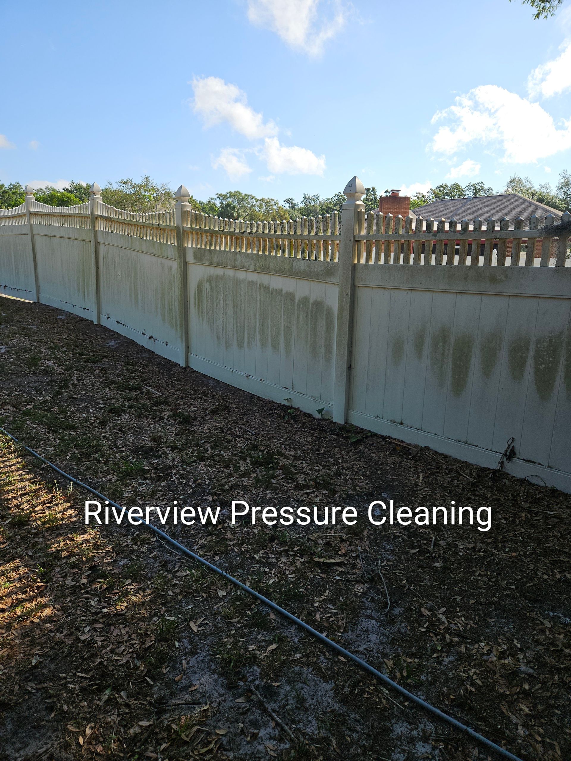 Concrete retaining wall with fence on a sunny day, watermark reading “Riverview Pressure Cleaning”