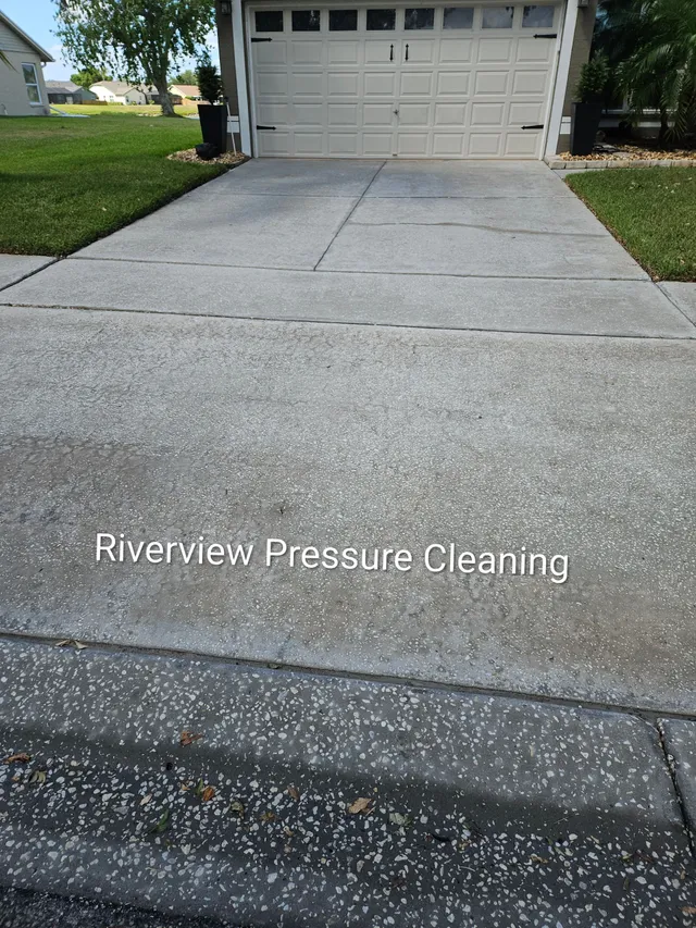 Driveway leading to a closed garage, with a pressure-cleaned concrete surface and lawn on the left.