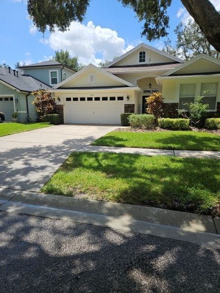 Suburban house with a two-car garage, driveway, and green front lawn under a bright sky