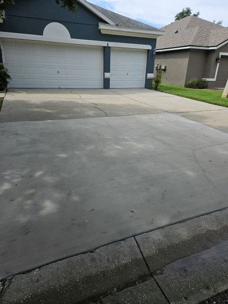Concrete driveway in front of a gray garage and suburban house, viewed from the street.