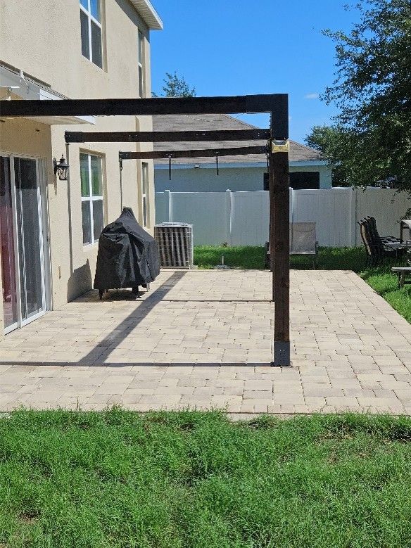 Paver patio and vinyl fence with dirt, weeds, algae, and mildew buildup in Gibsonton