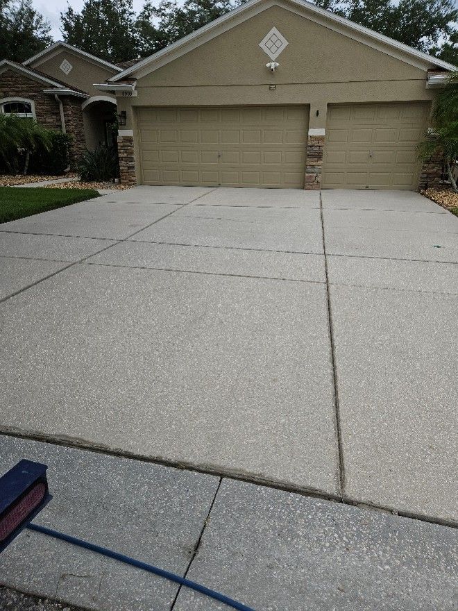Concrete driveway leading to a two-car garage with beige doors and a house front porch