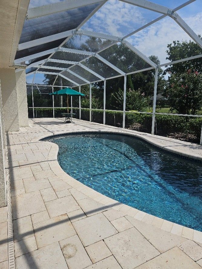 Clean pool cage, bright screens, and freshly pressure washed pool deck after exterior cleaning in Valrico.