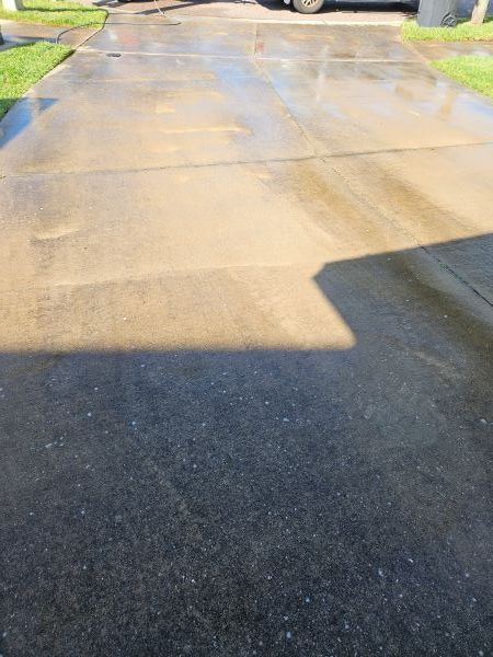 Wet residential driveway with bright sunlight and shadows on the pavement