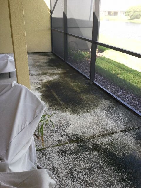 A dirty patio with a screened in porch and chairs.