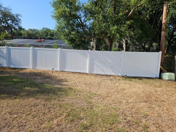 A white fence is sitting in the middle of a grassy field.